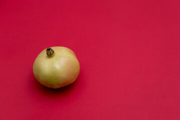 Ripe yellow pomegranate on a red background.
