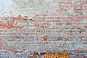 Red brick wall shabby weathered old grunge texture with marks of plaster and concrete background