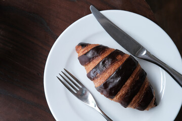 Chocolate croissant on white dish in cafe