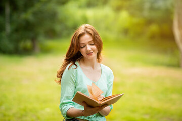 Beautiful Dreamy Redhead Girl Reading Book In Park, Enjoying Time Outdoors