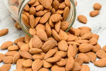 Almond nuts on the white rustic wooden background.