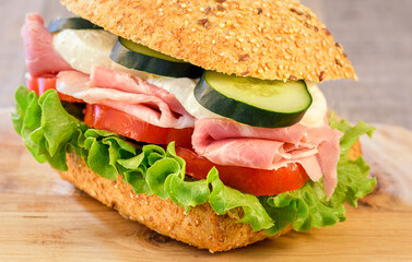 Rustic sandwich with ham, tomato, cucumber, mozzarella and green salad sheets.