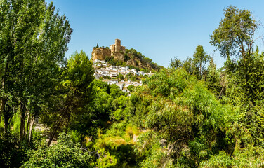 A view of the hilltop fortress in the town of Montefrio, Spain viewed through a gap in the trees in the summertime