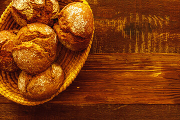Fresh bread rolls in basket on wooden table