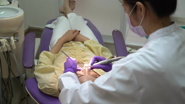 asian dentist clean tooth of young woman patient in dental clinic. dentistry and healthcare concept