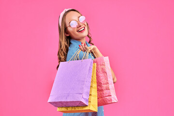 Lovely woman with shopping bags over pink background