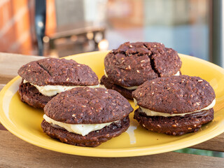 Fototapeta premium Chocolate and sesame yo-yo's chocolate biscuits or cookies on a yellow plate outdoors
