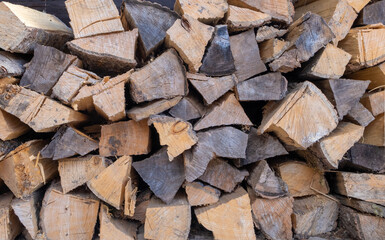 Firewood for stove heating, stacked in a woodpile. Horizontal orientation, selective focus.