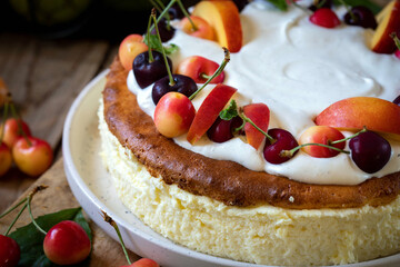 Cheesecake garnished with whipped cream, cherries and peaches.

