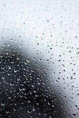 Raindrops dripping on glass out of focus with blurred background