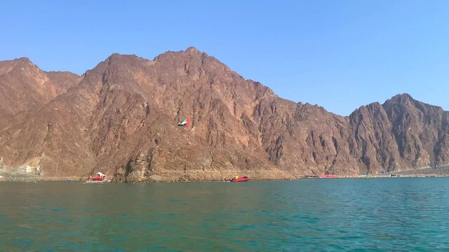 Beautiful deep green Hatta lake between Hajar Mountains with boats . Hatta dam in UAE. 