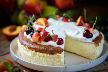 Cheesecake garnished with whipped cream, cherries and peaches.
