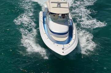 Elevated head on view of a white and blue sport fishing boat speeding on Biscayne Bay.