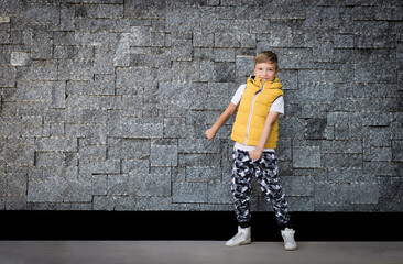 Happy boy doing floss dance against the wall.