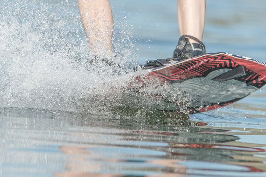 close-up of a boy's legs riding wake board in a lake
