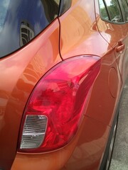 The red headlight on an orange car close-up.