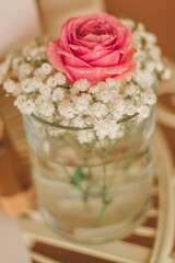 Beautiful close-Up of fresh pink rose, wihite small flowers in a elegant vase with water. Decoration concept for celebration.