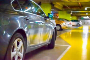 Obraz na płótnie Canvas Parking lot cars blurred. Car lot parking space in underground city garage. Empty road asphalt background in soft focus. Industrial Shed or Parking Lot.