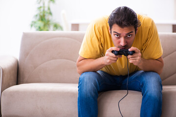 Young man playing joystick games at home