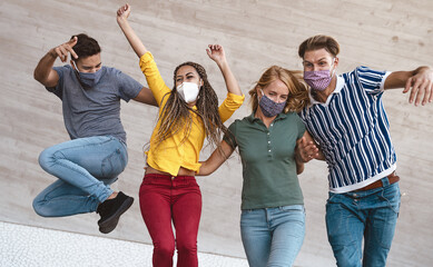 Young friends dancing together while wearing face mask outdoor - Happy people having fun in city...