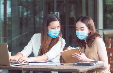 Two women wearing masks and working together