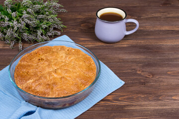 Fresh baked pie on a dark wooden surface with a cup of tea and linden blossom. Place for an inscription.