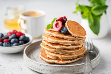 Fototapeta na wymiar Healthy oat pancakes with berries on a craft ceramic plate. Vegan breakfast food
