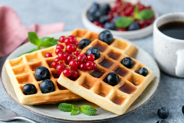 Belgian waffles with berries, square shape. Sweet dessert waffles served with cup of black coffee