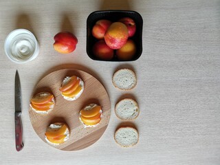  sandwiches with cream cheese, fresh nectarines slices on a serving wooden plank and ingredients. 