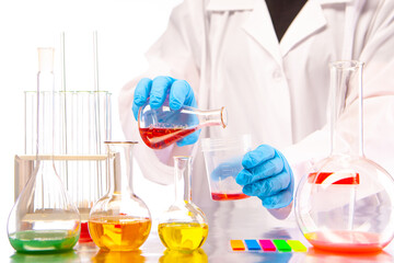 Chemical show. Demonstration of experiments with multicolored chemical liquids. Mixing of substances in test tubes. Chemist's hands close up. Laboratory glassware.