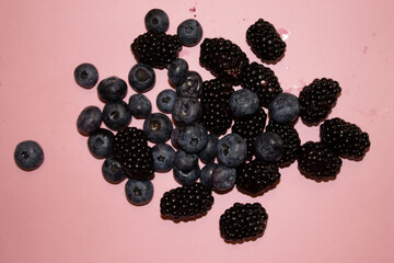 Blueberries and blackberries on a pink background