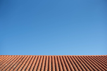cielo azul sobre tejado de tejas rojas