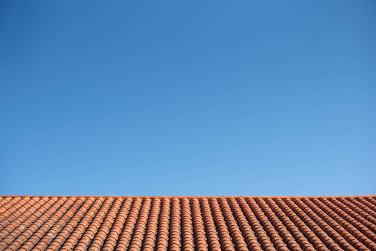 cielo azul sobre tejado de tejas rojas