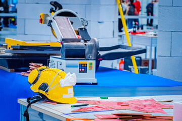 Preparation for laying out a pattern of tiles. Circular saw on stone and tiles. The saw for stone is installed in a building under construction. Saw for stone, construction helmet and tiles.