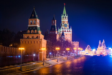 Fototapeta na wymiar Evening Moscow. Towers of the Moscow Kremlin against the dark sky. Spasskaya tower of the Kremlin with chimes. The building of the Historical Museum is decorated with garlands. Red square in Moscow.
