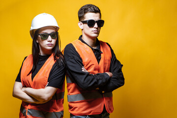 A man and a woman in orange vests and black glasses. A young couple on an orange background. Man...