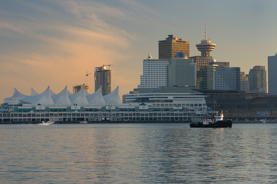 Downtown Vancouver and Canada Place at dusk with tugboat and seaplanes