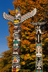 Kakasolas and Chief Wakas totem poles in Stanley Park Vancouver with orange maple leaves