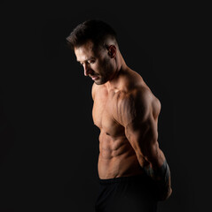 Fototapeta premium Handsome muscular male bodybuilder on a black background. Strong man.
