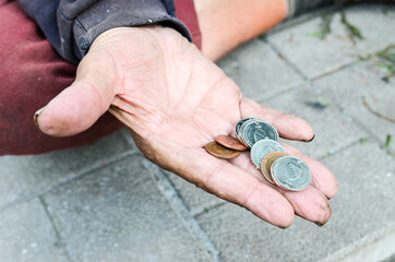 Poor man begging for money. Hand of an old man holding coins. Hungry and homeless male asking for...
