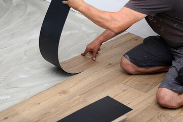 The worker installing new vinyl tile floor - obrazy, fototapety, plakaty