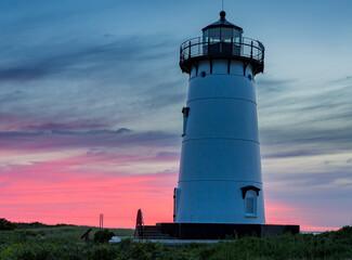 Soft clouds reflect morning sunrise colors behind Edgartown lighthouse in Martha's Vineyard