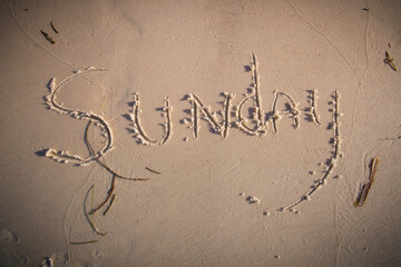 Sunday written on beach sand