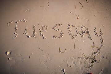 Tuesday written on beach sand