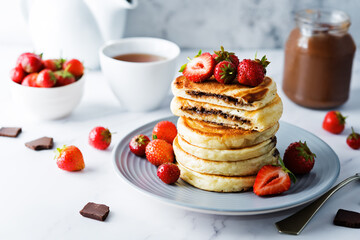 Pancakes with chocolate nutella filling decorated with strawberries