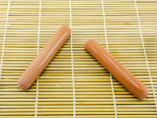two sausages on a wooden mat close up