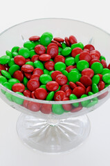 Green and red chocolate Christmas candies in a crystal bowl on white background