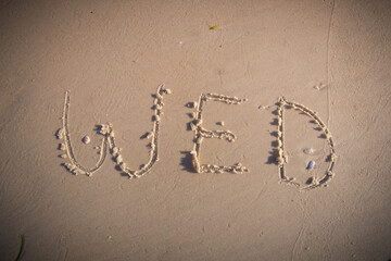 Wed. written on beach sand