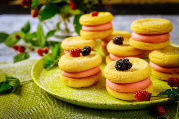 Cookies sandwiches with pink cream and wildberry.