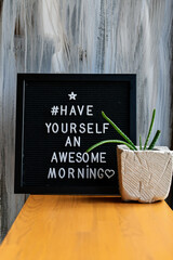 "Have yourself an awesome morning" words inscripted on black letterbox at the window on grunge background.